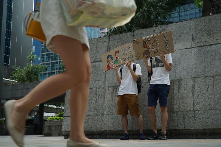 Protestors hold up signs to apologize for a demonstration that jammed the entrance of a government tax office in Hong Kong on Tuesday, June 25, 2019. Hong Kong protestors handed out flyers, held up signs, and bowed to passersby Tuesday to apologize for a sit-in demonstration the day before that blocked access to a government office for nearly two hours. (AP Photo/Dake Kang)