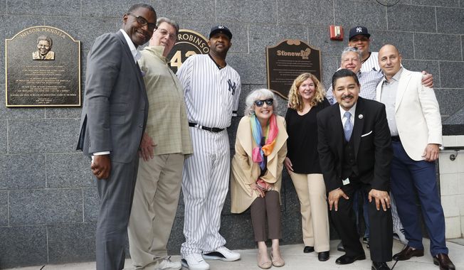 Representatives of the the Stonewall Inn and the New York Yankees, including pitcher CC Sabathia, third from left; relief pitcher Dellin Betances, second from right; assistant general manager Jean Afterman, center; and general manager Brian Cashman, right, honor the 50th anniversary of the Stonewall Inn Uprising after the Yankees unveiled a plaque in Monument Park before a baseball game Tuesday, June 25, 2019, in New York. Stonewall witness Tree Sequoia, second from left, and Stonewall owner co-owner Kurt Kelly, third from right, in front of Betances, joined the group. (AP Photo/Kathy Willens)