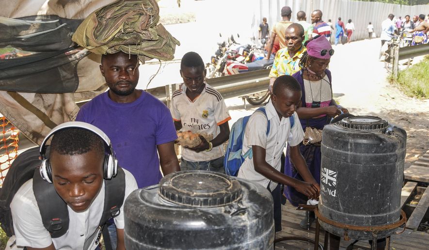 Women coming from Congo wash their hands with chlorinated water to prevent the spread of infection, at the Mpondwe border crossing with Congo, in western Uganda Friday, June 14, 2019. In Uganda, health workers had long prepared in case the Ebola virus got past the screening conducted at border posts with Congo and earlier this week it did, when a family exposed to Ebola while visiting Congo returned home on an unguarded footpath. (AP Photo/Ronald Kabuubi)