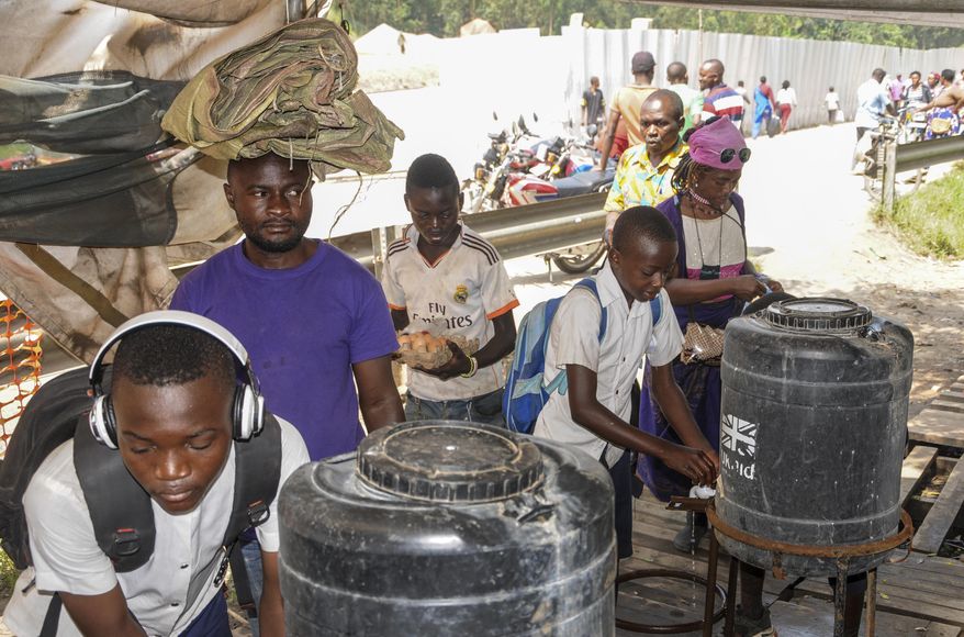 Women coming from Congo wash their hands with chlorinated water to prevent the spread of infection, at the Mpondwe border crossing with Congo, in western Uganda Friday, June 14, 2019. In Uganda, health workers had long prepared in case the Ebola virus got past the screening conducted at border posts with Congo and earlier this week it did, when a family exposed to Ebola while visiting Congo returned home on an unguarded footpath. (AP Photo/Ronald Kabuubi)