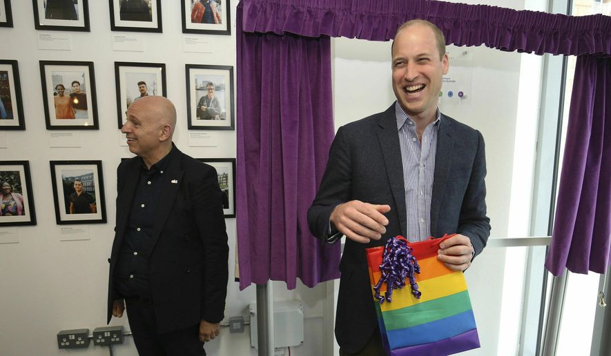 Britain's Prince William, the Duke of Cambridge, reacts to receiving a gift bag from trust chief executive officer Tim Sigsworth, during a visit to the Albert Kennedy Trust to learn about the issue of LGBTQ youth homelessness and the unique approach that the organisation is taking to tackling the problem, in London, Wednesday, June 26, 2019. (Jonathan Brady/Pool Photo via AP)