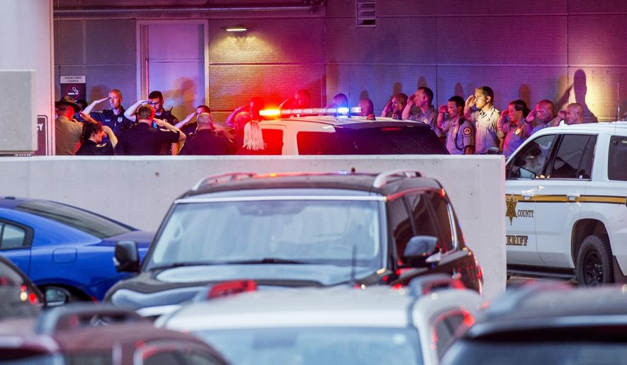 In this Tuesday, June 25, 2019 photo, law enforcement officers from numerous jurisdictions in central Illinois salute at the emergency entrance at OSF Saint Francis Medical Center in Peoria, Ill., as the body of Fulton County Sheriff's Deputy Troy Chisum arrives. Authorities say the sheriff's deputy died after being shot while responding to a call in Avon, Ill., where a suspect was barricaded in a home. (David Zalaznik/Journal Star via AP)