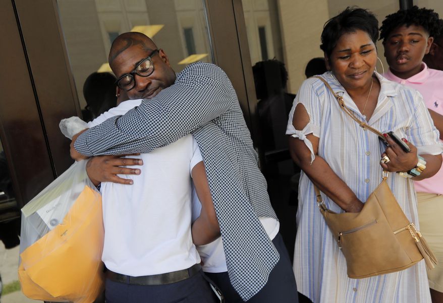Royal Clark, Jr., who was convicted of armed robbery in 2003, hugs his son Royal Clark III after walking out of the Jefferson Parish jail in Gretna, La., Thursday, June 27, 2019. At right is his mother Catherine Clark. Judge Donnie Rowan, of the 24th Judicial Court, vacated Clark's conviction based on fingerprint evidence brought forth by Innocence Project New Orleans. (AP Photo/Gerald Herbert)