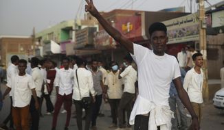 A protester flashes the victory sign, as others block a road during a protest, in Khartoum, Sudan, Monday, June 24, 2019. The United Nations&#39; top human rights official is urging Sudan&#39;s military rulers to allow her office to investigate a deadly crackdown on pro-democracy protesters. (AP Photo/Hussein Malla)