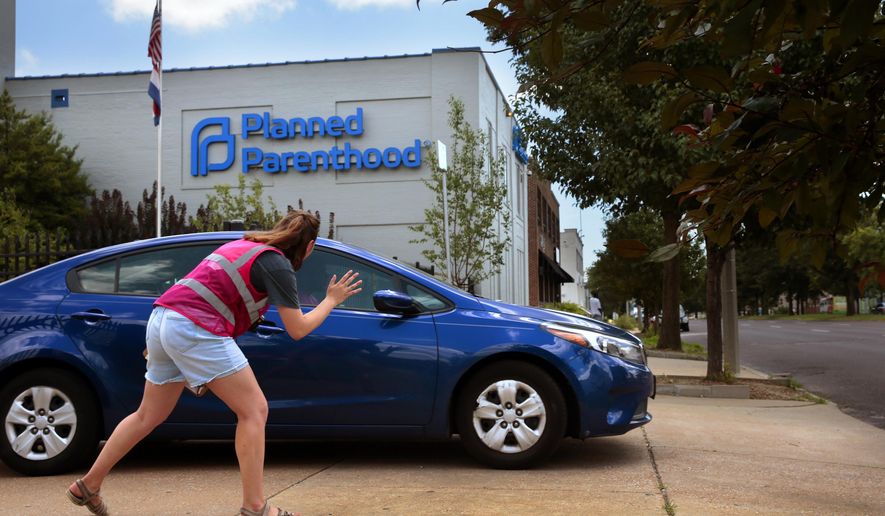Ashlyn Myers of the Coalition for Life St. Louis waves to a Planned Parenthood staff member on Friday, June 28, 2019. The Missouri Administrative Hearing Commission issued an order Friday allowing the clinic to continue performing abortions until it takes up its case later this year. (Robert Cohen/St. Louis Post-Dispatch via AP)