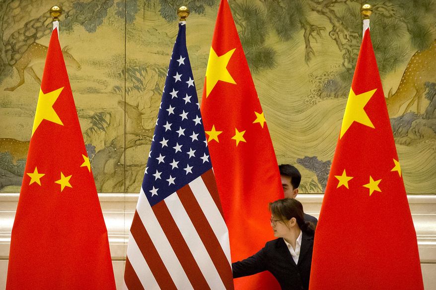 FILE - In this Feb. 14, 2019, file photo, Chinese staffers adjust U.S. and Chinese flags before the opening session of trade negotiations between U.S. and Chinese trade representatives at the Diaoyutai State Guesthouse in Beijing. Beijing on Friday, June 28, 2019, criticized what it calls "negative content" about China in legislation before the U.S. Congress, saying it would further damage relations already roiled by disputes over trade and technology. (AP Photo/Mark Schiefelbein, File)