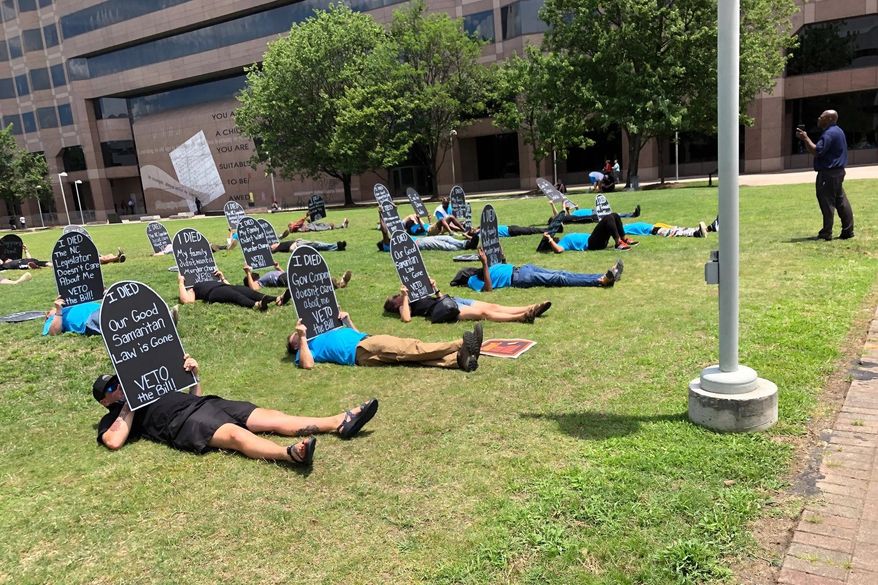 In this Wednesday, June 26, 2019 photo, activists lay down with tombstones in front of North Carolina's General Assembly building in Charlotte, N.C., during a protest against a bill that would charge people who sell drugs related to an overdose death with a high-level felony. Protesters say the bill will deter drug-users from calling 911 to report overdoses and will contribute to more overdose deaths. (Louise Beale-Vincent via AP)
