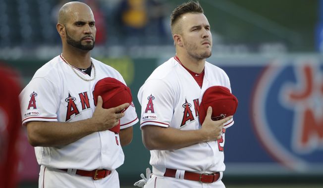 Los Angeles Angels' Albert Pujols, left, and Mike Trout listen to the national anthem before the team's baseball game against the Oakland Athletics on Friday, June 28, 2019, in Anaheim, Calif. (AP Photo/Marcio Jose Sanchez)