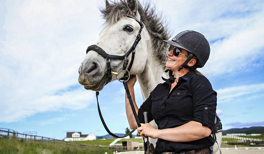 In a June 19, 2019 photo, Danica Yates, a dressage instructor and member of the Freedom Horse Farm, pets her horse Crystal in the Triple Take Arena west of Kalispell, Mont. Chrystal is one of several horses Yates has rescued throughout her years as a trainer. (Hunter D'Antuono/Flathead Beacon via AP)