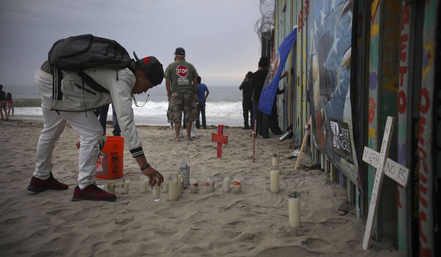 Candles are placed next to the border fence that separates Mexico from the United States, in memory of migrants who have died during their journey toward the U.S., in Tijuana, Mexico, late Saturday, June 29, 2019. (AP Photo/Emilio Espejel)