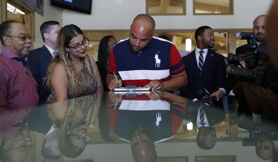 Jovan Jackson, center, registers to vote following a news conference Monday, July 1, 2019, in North Las Vegas, Nev. Jackson became eligible to vote when a law that automatically restores the right to vote for formerly incarcerated individuals took effect Monday in Nevada. (AP Photo/John Locher)