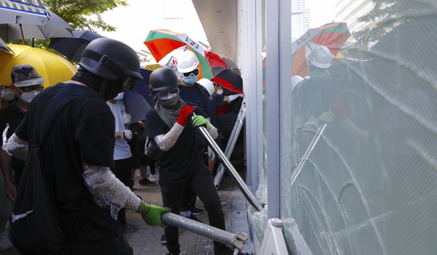 Protesters try to break the glass walls of the Legislative Council in Hong Kong on Monday, July 1, 2019. Combative protesters tried to break into the Hong Kong legislature Monday as a crowd of thousands prepared to start a march in that direction on the 22nd anniversary of the former British colony&#39;s return to China. (AP Photo/Vincent Yu)