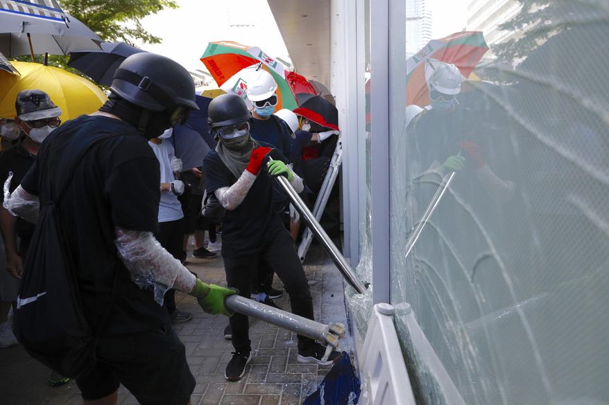 Protesters try to break the glass walls of the Legislative Council in Hong Kong on Monday, July 1, 2019. Combative protesters tried to break into the Hong Kong legislature Monday as a crowd of thousands prepared to start a march in that direction on the 22nd anniversary of the former British colony&#39;s return to China. (AP Photo/Vincent Yu)