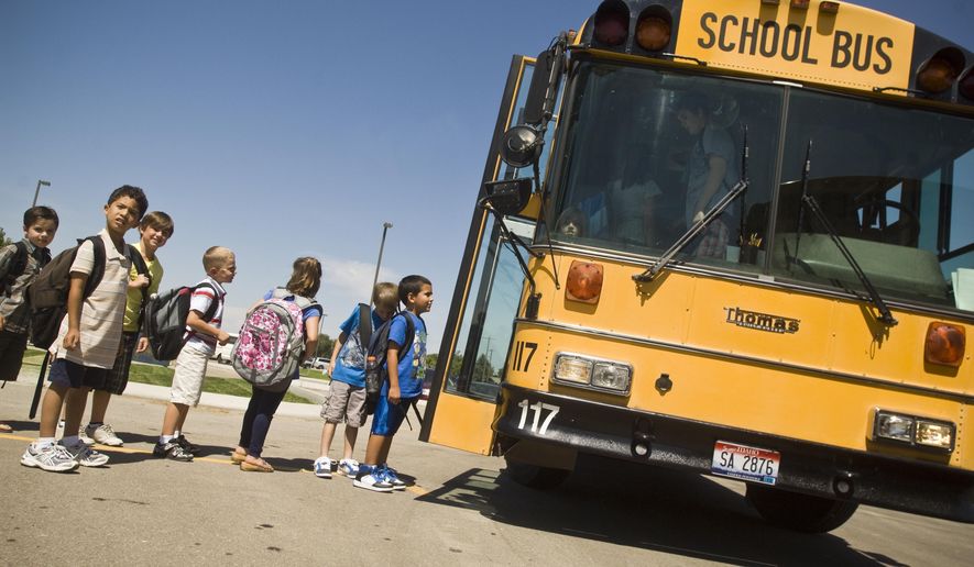 FILE - In this Aug. 9, 2010 file photo, Students from Liberty Charter School in Nampa, Idaho wait to board a bus after the first day of the new school year. Lawmakers increased fines for motorists unlawfully passing a loading or unloading school bus, with fines up to $1,000 for each consecutive offense. (Charlie Litchfield/The Idaho Press-Tribune via AP, File)