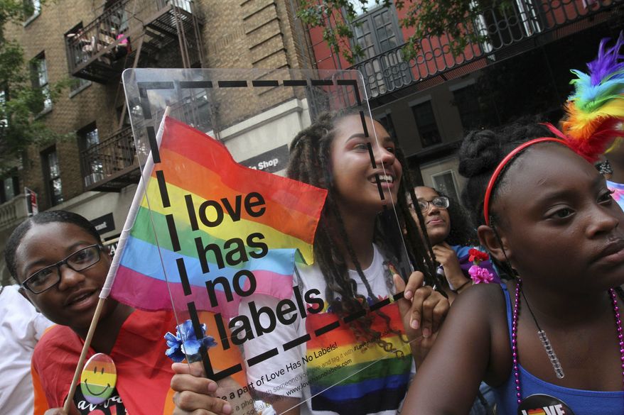 Holding a clear sign, Kaylah Denton, 15, of Poughkeepsie, New York, center, watches the LGBTQ Pride march, Sunday, June 30, 2019, in New York. (AP Photo/Tina Fineberg)