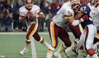 FILE - In this Jan. 26, 1992, file photo, Washington Redskins quarterback Mark Rypien, left, drops to pass during NFL football&#39;s Super Bowl XXVI in Minneapolis. Rypien has been arrested in Washington state on suspicion of domestic violence. The Spokesman-Review cites Spokane police saying Rypien was facing a charge of fourth-degree assault.Rypien, 56, was processed at the Spokane County Jail at around 6:30 p.m. Sunday and was awaiting a court appearance Monday, July 1, 2019. (AP Photo/Jim Mone, File)