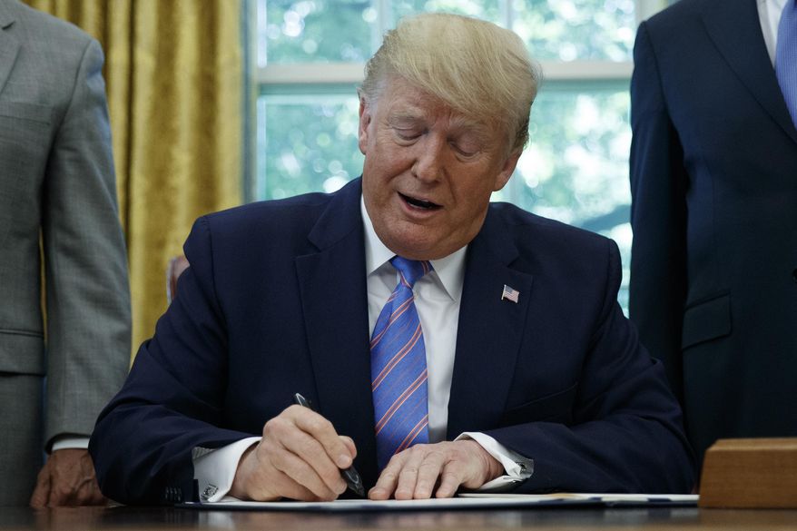 President Donald Trump signs a $4.6 billion aid package to help the federal government cope with the surge of Central American immigrants at the U.S.-Mexico border during a ceremony in the Oval Office of the White House in Washington, Monday, July 1, 2019. (AP Photo/Carolyn Kaster)