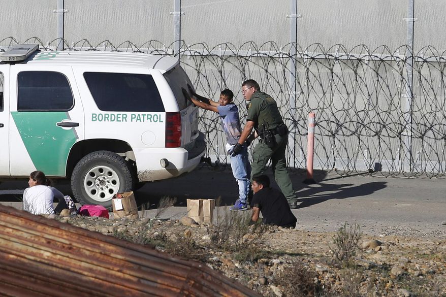 FILE - In this Dec. 15, 2018, file photo, Honduran asylum seekers are taken into custody by U.S. Border Patrol agents after the group crossed the U.S. border wall into San Diego, Calif., seen from Tijuana, Mexico. Immigrant rights activists on Friday, June 28, 2019, asked a U.S. judge to block a new Trump administration policy that would keep thousands of asylum seekers locked up while they pursue their cases, instead of giving them a chance to be released on bond. (AP Photo/Moises Castillo, File)