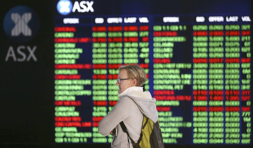 FILE - In this May 6, 2019, file photo, a woman looks at display boards at the Australian Stock Exchange in Sydney, Australia. Australia's central bank has cut its benchmark interest rate by a quarter of a percentage point to a new record low of 1% in a bid to boost the economy. (AP Photo/Rick Rycroft, File)