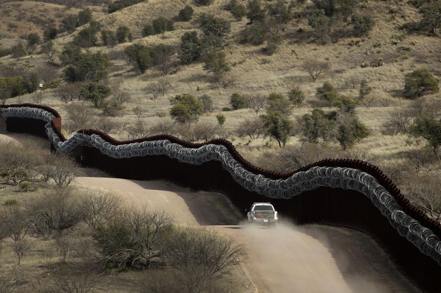 This March 2, 2019, file photo, shows a Customs and Border Control agent patrolling on the U.S. side of a razor-wire-covered border wall along the Mexico east of Nogales, Ariz. Federal prosecutors are getting ready to announce whether they'll retry a border activist after a U.S. jury was unable to reach a verdict against him on charges of conspiracy to transport and harbor migrants. (AP Photo/Charlie Riedel, File)