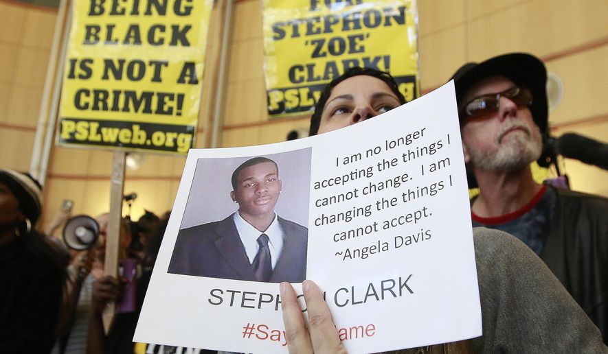 FILE - In this March 22, 2018, file photo, Anita Ross holds a photo of 22-year-old Stephon Clark, who was fatally shot by police, as she and other protesters block the entrance to Sacramento City Hall in Sacramento, Calif. A new report released Tuesday, July 2, 2019, by the state attorney general's office said the number of civilian deaths in police confrontations is down from each of the last two years, but included Stephon Clark, an unarmed black vandalism suspect killed by Sacramento police. (AP Photo/Rich Pedroncelli, File)