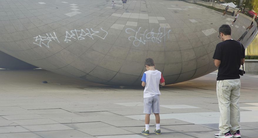Graffiti mars the popular giant metallic sculpture known as "The Bean," Tuesday, July 2, 2019, in Chicago. Police in Chicago have arrested seven people suspected of spray-painting graffiti on two downtown landmarks, including the popular giant metallic sculpture known as "The Bean." (Jermaine Nolen/Chicago Sun-Times via AP)