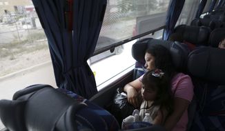A Central American migrant woman and child wait in a bus after deciding to voluntarily return to their country, in Ciudad Juarez, Mexico, Tuesday, July 2, 2019. Dozens of Central Americans who had been returned to the border city of Juarez to await the outcome of their U.S. asylum claims are being bused back to their countries Tuesday by Mexican authorities, a first for that size group of people in the program commonly known as “remain in Mexico.” (AP Photo/Christian Chavez)