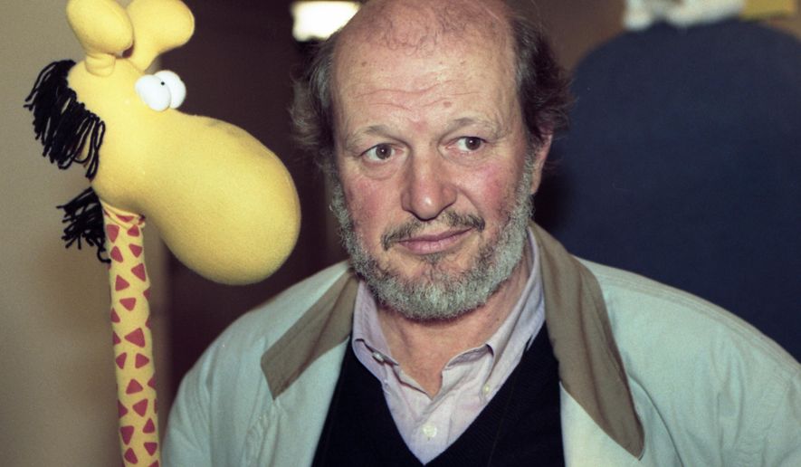 FILE - In this Sept, 3 1992 file photo, Argentinian cartoonist, Guillermo Mordillo, poses with a toy giraffe, a replica of the figure frequently appearing in his drawings at an exhibition held in honour of his 60th birthday in Hamburg, Germany. Mordillo, distinguished for his chubby figures with round noses that provoked both laughter and reflection, has died at age of 86. A post in his official Facebook profile on Monday, July 1, 2019 confirmed earlier Spanish media reports about the Argentinian artist’s death on Sunday in the Spanish island of Mallorca, where he spent long periods. (AP Photo/Chistian Eggers, File)