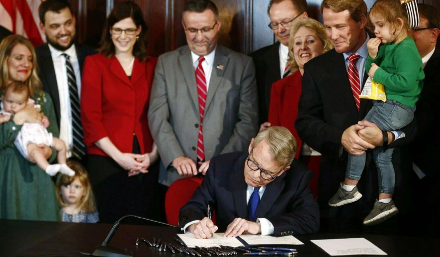 FILE - In this April 11, 2019 file photo, Gov. Mike DeWine signs a bill imposing one of the nation's toughest abortion restrictions, in Columbus, OH. A federal judge temporarily blocked the Ohio law Wednesday, July 3, 2019, that would ban abortions after a fetal heartbeat can be detected, allowing clinics to continue to provide the procedure as a legal faceoff continues. (Fred Squillante/The Columbus Dispatch via AP, File)