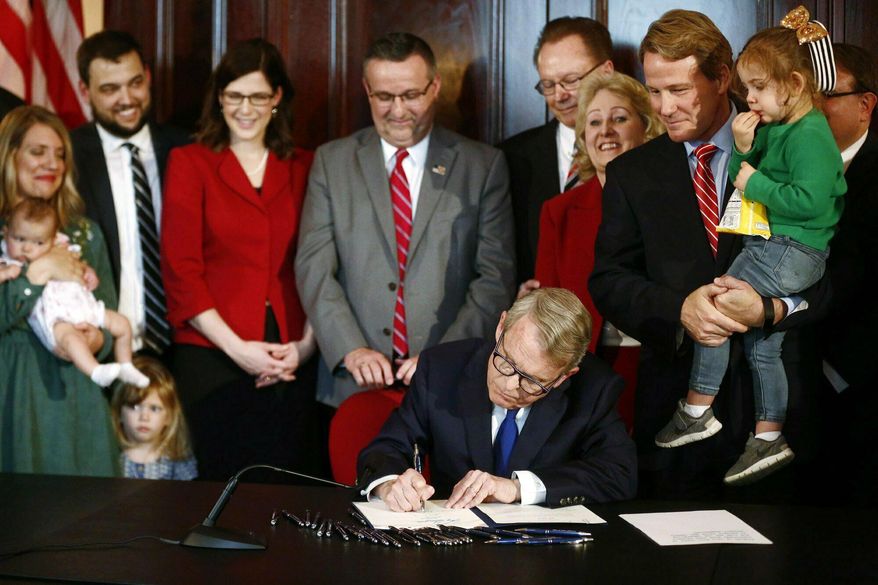 FILE - In this April 11, 2019 file photo, Gov. Mike DeWine signs a bill imposing one of the nation's toughest abortion restrictions, in Columbus, OH. A federal judge temporarily blocked the Ohio law Wednesday, July 3, 2019, that would ban abortions after a fetal heartbeat can be detected, allowing clinics to continue to provide the procedure as a legal faceoff continues. (Fred Squillante/The Columbus Dispatch via AP, File)