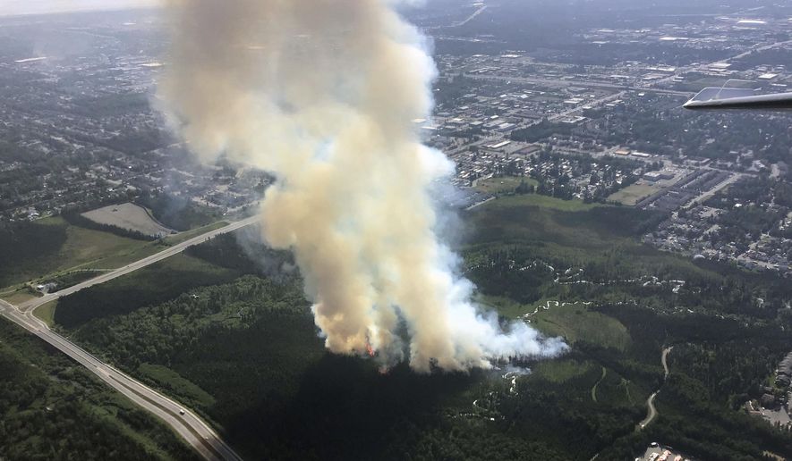 In this photo taken Tuesday, July 2, 2019, and provided by the Alaska Division of Forestry, smoke rises from a wildfire in east Anchorage, Alaska. A fast-moving brush fire caused the temporary evacuations of a trailer home park and a science center in east Anchorage on Tuesday afternoon. Smoke from the fire raised a plume over Alaska's largest city that could be seen for miles. (Jason Jordet/Alaska Division of Forestry via AP)