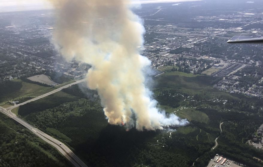 In this photo taken Tuesday, July 2, 2019, and provided by the Alaska Division of Forestry, smoke rises from a wildfire in east Anchorage, Alaska. A fast-moving brush fire caused the temporary evacuations of a trailer home park and a science center in east Anchorage on Tuesday afternoon. Smoke from the fire raised a plume over Alaska's largest city that could be seen for miles. (Jason Jordet/Alaska Division of Forestry via AP)