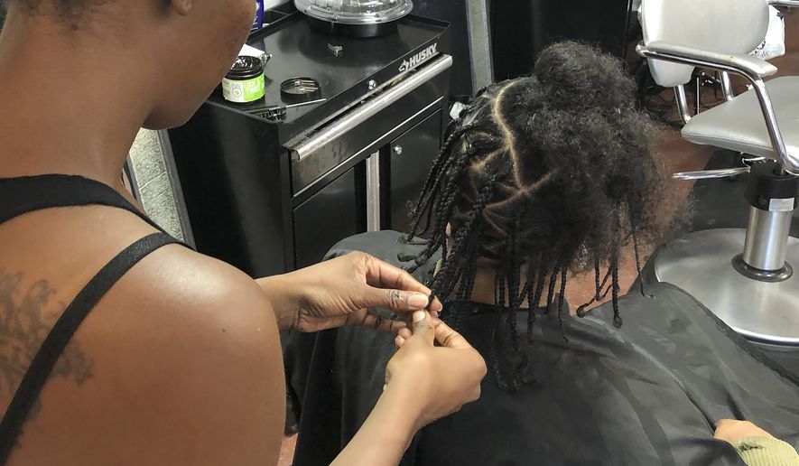 Shana Bonner, left, styles the hair of Pho Gibson at Exquisite U hair salon in Sacramento, Calif., Wednesday, July 3, 2019. California is the first state to ban job and school discrimination against people for wearing natural hair styles such as braids. (AP Photo/Kathleen Ronayne)
