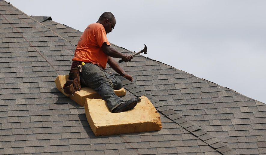 In this June 19, 2019, photo a worker balances on a steep roof as he lays down shingles on a roof on a new house in a Brandon, Miss., neighborhood. On Wednesday, July 3, the Institute for Supply Management, a trade group of purchasing managers, issues its index of non-manufacturing activity for June. (AP Photo/Rogelio V. Solis)