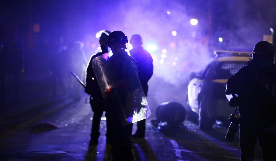 In this Nov. 25, 2014, file photo, police officers watch protesters as smoke fills the streets in Ferguson, Mo. The city of Ferguson needs to make more progress on implementing the 2016 consent decree, federal officials and an independent monitor told a federal judge Tuesday, July 2, 2019. (AP Photo/Charlie Riedel, File)
