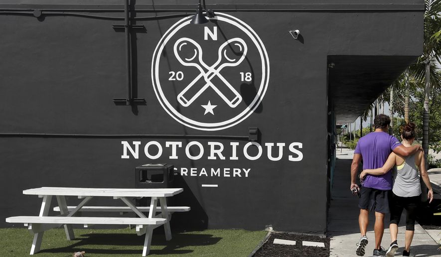 ADVANCE RELEASE FOR THURSDAY, JULY 4, 2019, AT 12:01 A.M. EDT AND THEREAFTER.. In this Thursday, June 20, 2019 photo, a couple walks together past Notorious Creamery at the Hive, a group of warehouses behind the former Sears, that have been converted to retail and restaurants in the Flagler Village neighborhood of Fort Lauderdale, Fla. (Amy Beth Bennett/South Florida Sun-Sentinel via AP)
