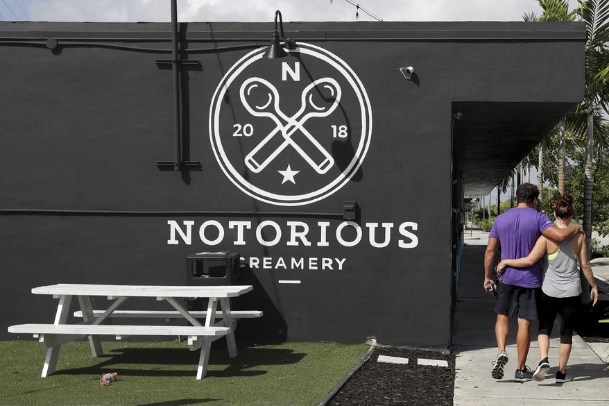 ADVANCE RELEASE FOR THURSDAY, JULY 4, 2019, AT 12:01 A.M. EDT AND THEREAFTER.. In this Thursday, June 20, 2019 photo, a couple walks together past Notorious Creamery at the Hive, a group of warehouses behind the former Sears, that have been converted to retail and restaurants in the Flagler Village neighborhood of Fort Lauderdale, Fla. (Amy Beth Bennett/South Florida Sun-Sentinel via AP)