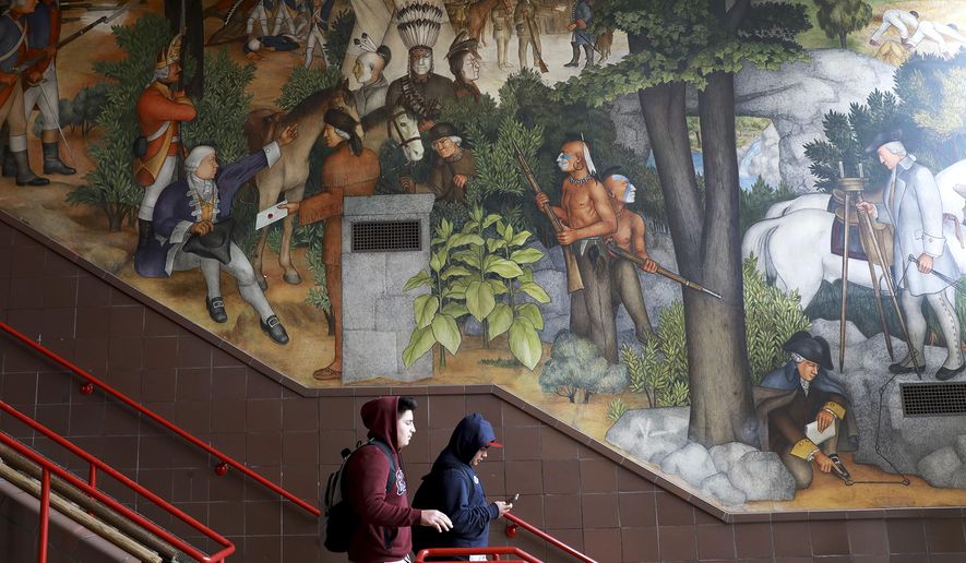 In this photo taken April 3, 2019, a pair of students walk past a historic mural that includes slaves and a dead Native American at George Washington High School in San Francisco. The San Fransisco school board unanimously voted Tuesday, June 25, 2019, to destroy a controversial mural displayed in a public high school. This is the latest move in recent times to remove New Deal-era art, now considered offensive. (Yalonda M. James/San Francisco Chronicle via AP)
