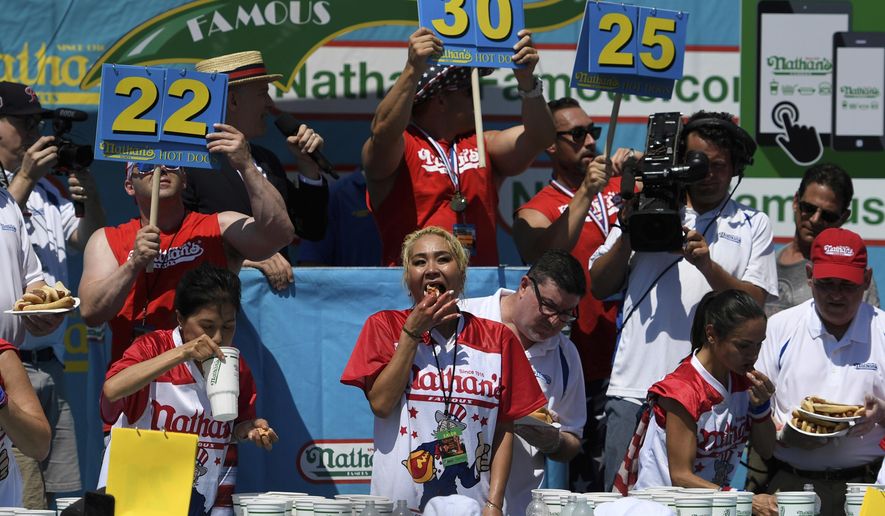Juliet Lee, left, Miki Sudo, center, and Michelle Lesko, right, compete in the closing moments of the women&#39;s competition of the Nathan&#39;s Famous July Fourth hot dog eating contest, Thursday, July 4, 2019, in New York&#39;s Coney Island. (AP Photo/Sarah Stier)
