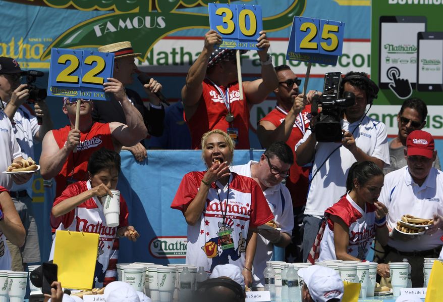 Juliet Lee, left, Miki Sudo, center, and Michelle Lesko, right, compete in the closing moments of the women&#39;s competition of the Nathan&#39;s Famous July Fourth hot dog eating contest, Thursday, July 4, 2019, in New York&#39;s Coney Island. (AP Photo/Sarah Stier)
