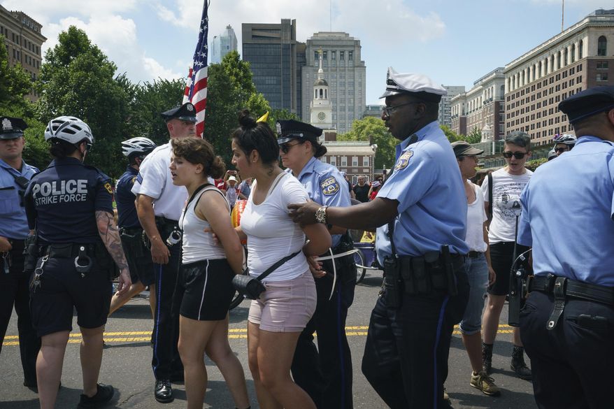 Police arrest protestors who interrupted the Salute to America Independence Day Parade, on Thursday, July 4, 2019 in Philadelphia. The protestors originally gathered outside the Department of Homeland Security Immigration and Customs Enforcement office and marched to the parade at Independence Hall, (Jessica Griffin/The Philadelphia Inquirer via AP)