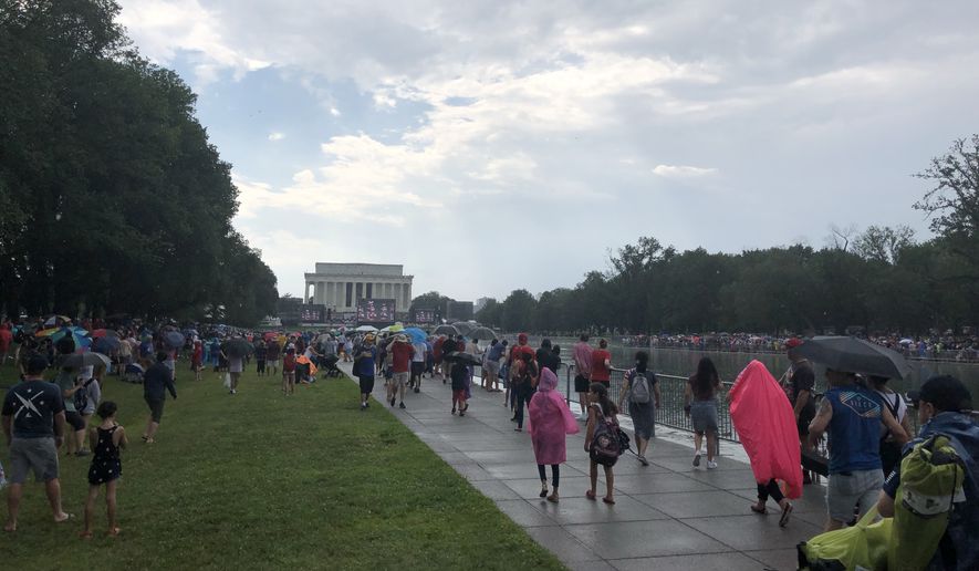 People on the National Mall take cover from a passing storm during Independence Day festivities on Thursday, July 4, 2019. (Photo by Moss Brennan / The Washington Times)