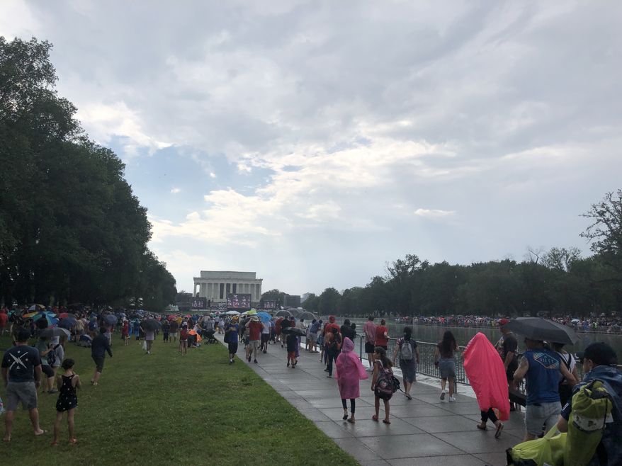 People on the National Mall take cover from a passing storm during Independence Day festivities on Thursday, July 4, 2019. (Photo by Moss Brennan / The Washington Times)