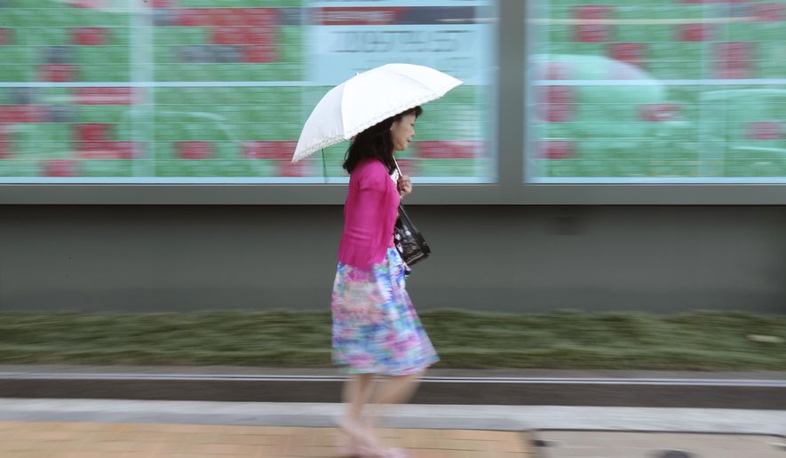 In this June 18, 2019, photo, a woman walks by an electronic stock board of a securities firm in Tokyo. Asian stocks fell Friday as investors waited for American employment data and details of U.S.-Chinese trade talks. (AP Photo/Koji Sasahara)
