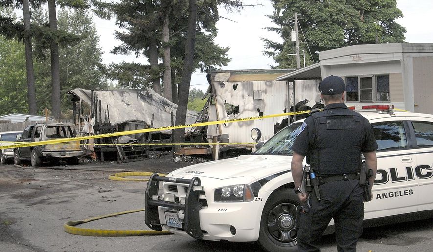 Port Angeles police Officer T.J. Mueller looks over the scene of a fire that destroyed two mobile homes and left several dead early Saturday, July 6, 2019, at the Welcome Inn RV Park in Port Angeles, Wash. Multiple people are believed to be dead following a fire at a mobile home park site in western Washington. The Peninsula Daily News reports the fire at the Welcome Inn RV Park in west Port Angeles broke out about 2:30 a.m. Saturday. (Keith Thorpe/The Peninsula Daily News via AP)