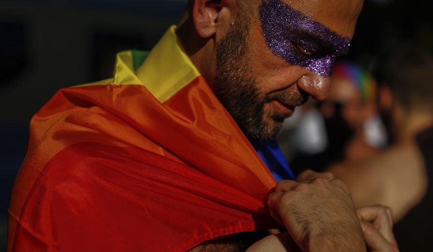 A reveller adjusts the rainbow flag during the LGBTQ pride parade in Madrid, Spain, Saturday, July 6, 2019. (AP Photo/Manu Fernandez)  ** FILE **