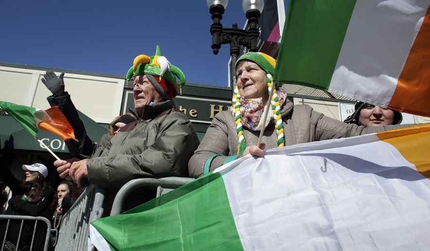 Dan O'Connell, center left, and his partner Myra O'Leary, center right, both of Cork, Ireland, display flags while watching the annual St. Patrick's Day parade, Sunday, March 18, 2018, in Boston. The city's 117th St. Patrick's Day Parade followed a shortened snow route used three of the past four years due to the buildup of snow from three recent nor'easters. O'Connell and O'Leary said they came to Boston for the weekend to watch the parade. (AP Photo/Steven Senne)