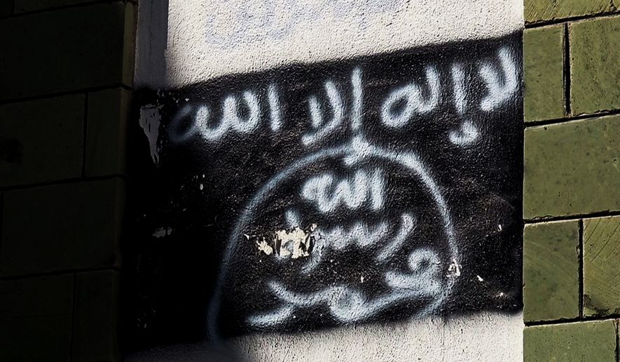The black al-Qaida flag is sprayed on the wall of a damaged school that was turned into a religious court, in Taiz, Yemen, shown in this Oct. 16, 2017, photo. Al-Qaida fighters and other militants poured into Taiz to help defend it against Shiite rebels who have besieged it since 2015, and now the extremists are intertwined with militias financed by the U.S.-backed coalition. (AP Photo)