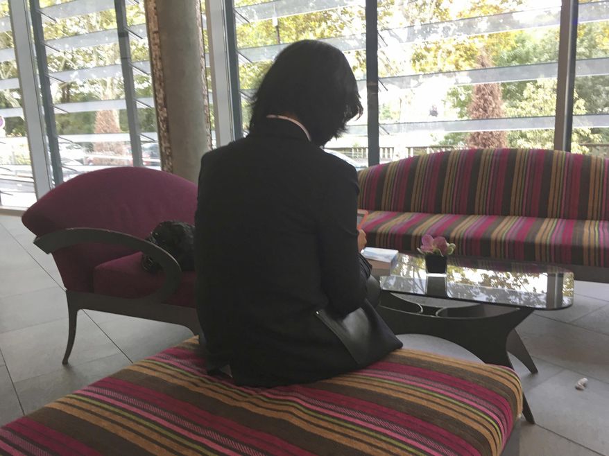 FILE - In this Oct. 7, 2018, file photo, Grace Meng, the wife of former Interpol President Meng Hongwei, who does not want her face shown, consults her mobile phone in the lobby of an hotel in Lyon, central France, where the police agency is based. Meng Hongwei has sued the international police agency, accusing it of failing to protect him from arrest in China and failing to protect his family. Grace Meng said in a statement on Sunday, July 7, 2019, that her lawyers filed a lawsuit in the Permanent Court of Arbitration in The Hague, Netherlands. She says Interpol “breached its obligations owed to my family” and “is complicit in the internationally wrongful acts of its member country, China.” (AP Photo/John Leicester, File)