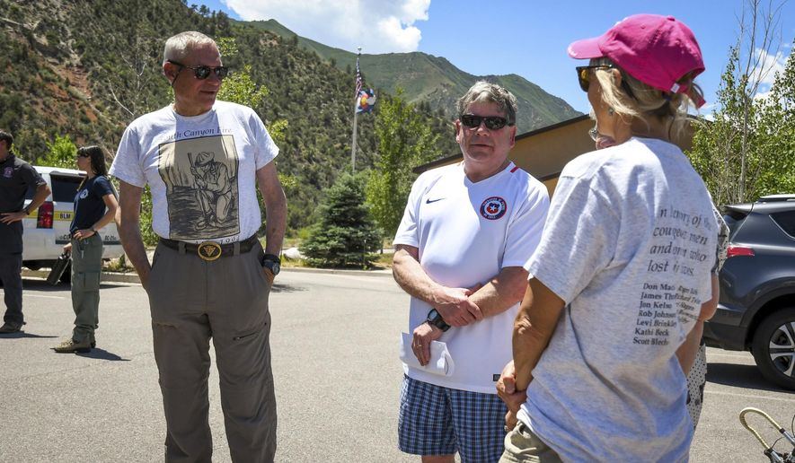 Family members of Roger Ross speak with New Castle, Colo., Mayor Art Riddile, second right, at the Storm King Fire press conference on Saturday, July 6, 2019, near Glenwood Springs, Colo., marking 25 years since the lives of 14 Wildland firefighters were lost on Storm King Mountain which looms in the background. (Chelsea Self/Glenwood Springs Post Independent via AP)